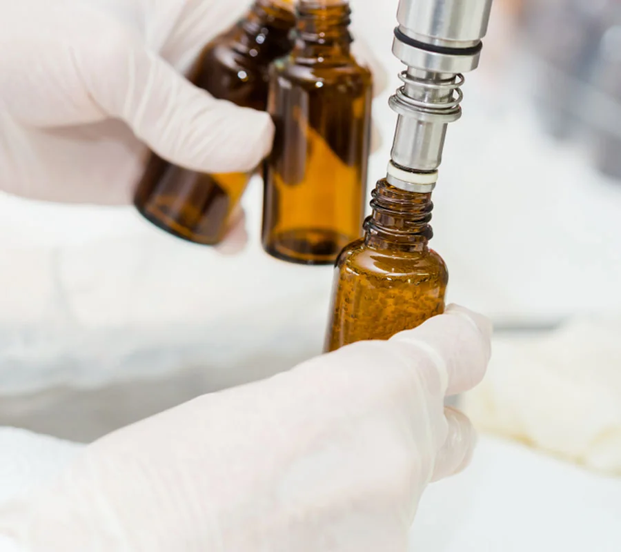 Amber serum bottles being filled by hand